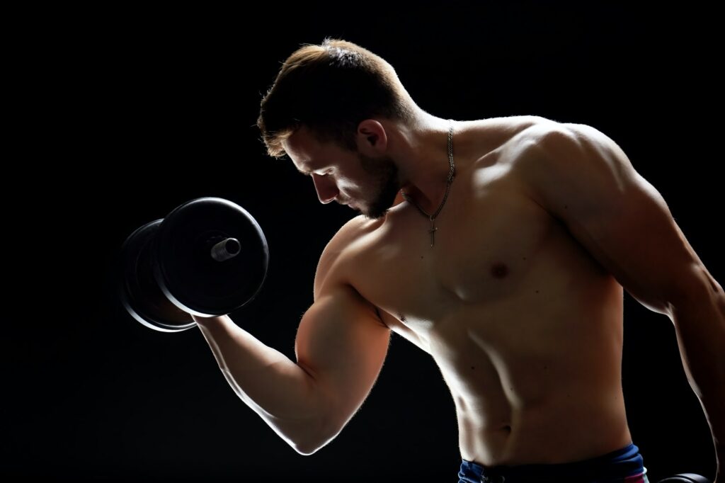 Muscular man doing dumbbell exercises